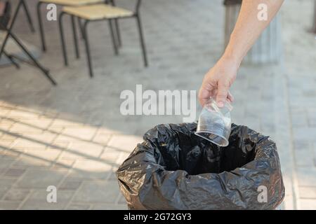 A man throws an empty plastic cup into a trash can Stock Photo