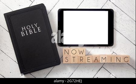 Now Streaming in Block Letters on a White Wooden Table with a Bible and Tablet Stock Photo