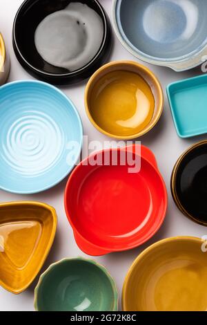 Collection of empty colorful ceramic bowls. Group of utensils captured from above, top view, flat lay against white background Stock Photo