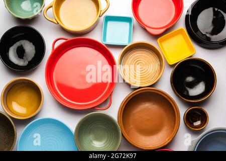 Collection of empty colorful ceramic bowls. Group of utensils captured from above, top view, flat lay against white background Stock Photo