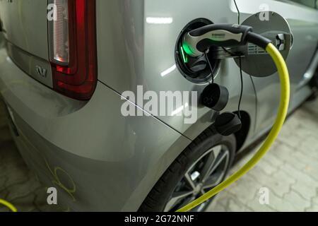 View at a charging electric car by a pluged in type 2 charging wire, green light is glowing as sysmbol for the active charge procedure. Stock Photo