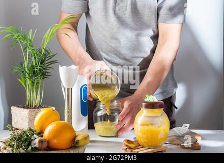 Pour the jam into a glass jar. Pour from jar to jar. The cook pours jam into jars. Front view. Stock Photo