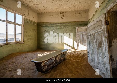 Abandoned building being taken over by encroaching sand in the old mining town of Kolmanskop near Luderitz, Namib Desert, Namibia. Stock Photo