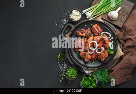 Pieces of fried meat with fresh onions on a black plate. Stock Photo