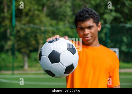 Closeup soccer ball in hand of young African American man on sports court  Stock Photo