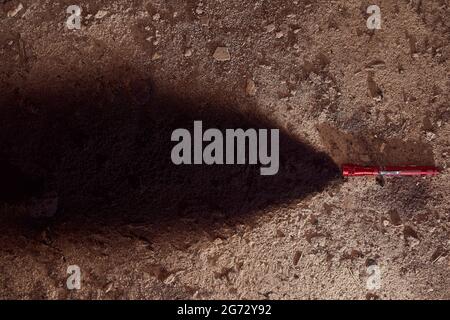 Conceptual photo. A red lantern shines with a black beam lying on brown earth Stock Photo