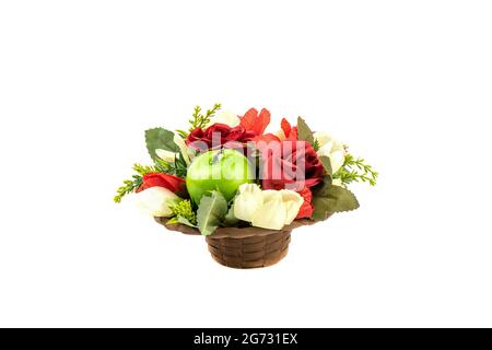 Flower arrangement of artificial roses and apples in a basket isolated on a white background. Copy space. Stock Photo