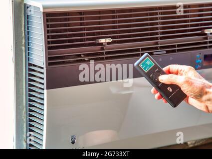 Man Using a Remote to control Window Air conditioning Unit, NYC, USA Stock Photo