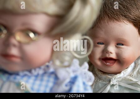 Vintage baby doll laughing at girl doll with glasses Stock Photo