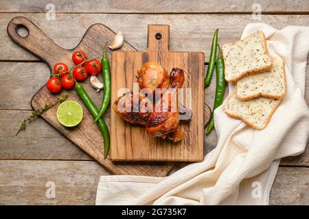 Board with roasted chicken legs on wooden background Stock Photo