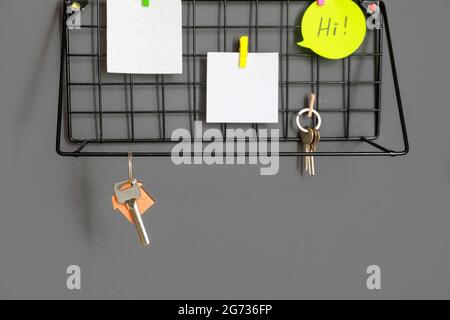 Shelf with keys and sticker notes hanging on dark wall Stock Photo