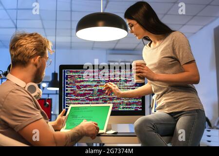 Young programmers working with laptop in office at night Stock Photo