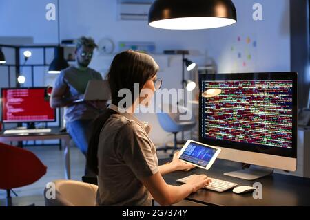 Female programmer working with computer in office at night Stock Photo