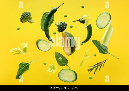 Flying green vegetables on color background Stock Photo