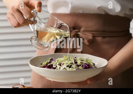 Female chef cooking tasty cabbage salad in kitchen, closeup Stock Photo