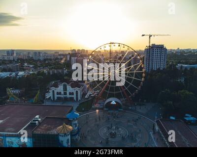 Ferris wheel spinning aerial sunset contrast view in Kharkiv city center, amusement Park of Maxim Gorky. High attraction for recreation and city obser Stock Photo