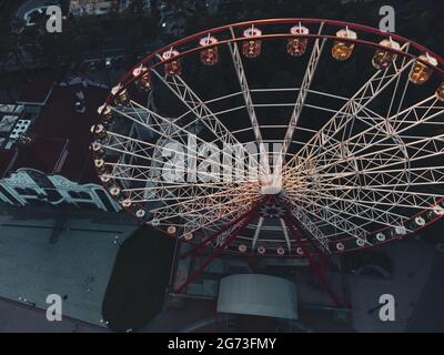 Ferris wheel spinning aerial top contrast view in Kharkiv city center, amusement Park of Maxim Gorky. High attraction for recreation and city observat Stock Photo