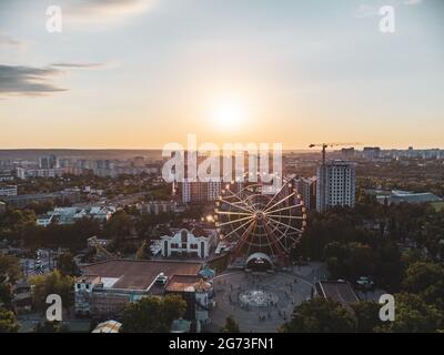 Ferris wheel spinning aerial sunset view in Kharkiv city center, amusement Park of Maxim Gorky. High attraction for recreation and city observation in Stock Photo