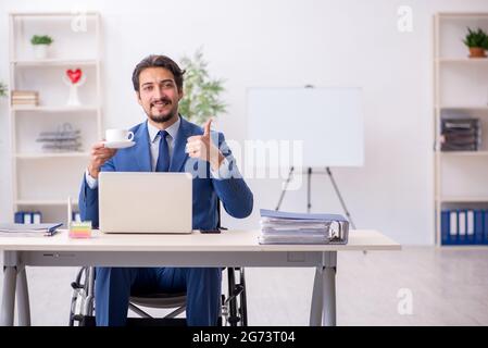 Young businessman employee in wheel-chair at workplace Stock Photo