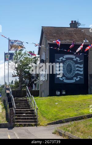 8 July 2021 Flags bunting and painted insignia adorn the local headquarters of the protestant UVF paramilitary association on Owebroe Drive in the Kil Stock Photo