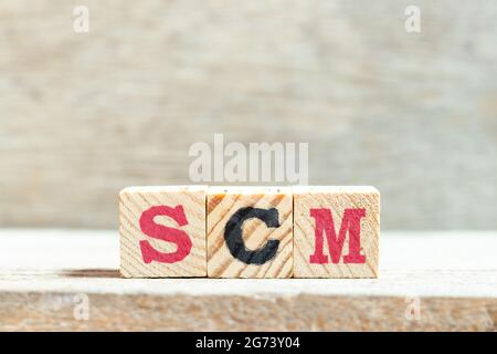 Alphabet letter block in word SCM (Abbreviation of Supply chain management) on wood background Stock Photo