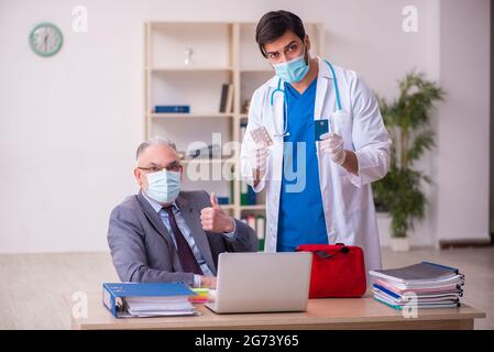 Young doctor visiting old businessman in the office Stock Photo