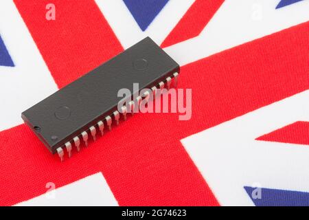 Close shot of integrated circuit / EPROM chip on small UK Union Jack flag. For UK semiconductor shortages, UK chip dependency, UK chip start-ups. Stock Photo