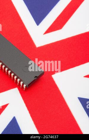 Close shot of integrated circuit / EPROM chip on small UK Union Jack flag. For UK semiconductor shortages, UK chip dependency, UK chip start-ups. Stock Photo