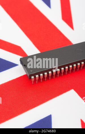 Close shot of integrated circuit / EPROM chip on small UK Union Jack flag. For UK semiconductor shortages, UK chip dependency, UK chip start-ups. Stock Photo