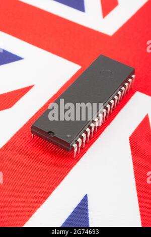 Close shot of integrated circuit / EPROM chip on small UK Union Jack flag. For UK semiconductor shortages, UK chip dependency, UK chip start-ups. Stock Photo