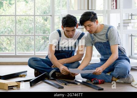 Two carpenters discussed the type of bench being assembled. Handyman installing wooden bench in new house. House renovation service. Morning work atmo Stock Photo