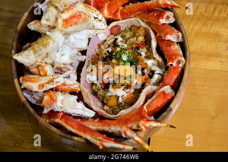Live TARABA King Crab steamed on wooden tray. Legs and claws were cut into pieces. Taraba fried rice are in the crab shell consists of tobiko, Ikura r Stock Photo
