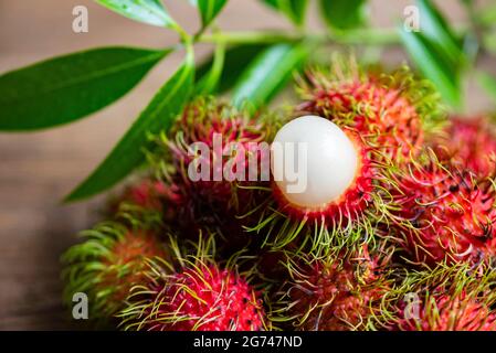 Fresh and ripe rambutan sweet tropical fruit peeled rambutan with leaves, Rambutan fruit on wooden background harvest from the garden Stock Photo