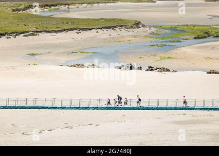 Barleycove, Cork, Ireland. 10th July, 2021. On a warm summers day holidaymakers cross a foot bridge over sand dunes as they walk to the beach at Barleycove, Co. Cork, Ireland. - Picture; David Creedon / Alamy Live News Stock Photo