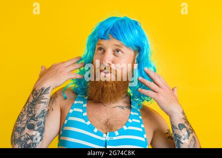 Happy man with life buoy, swimsuit and blue wig acts like a happy woman Stock Photo