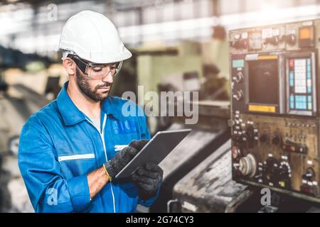 engineer setup the CNC machine with G-Code programming upload from Computer Tablet for technology in heavy industry. Stock Photo