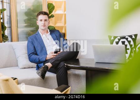 Smart handsome Caucasian businessman sitting relax waiting area in modern office. Stock Photo