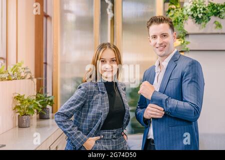 Portrait caucasian business man and women standing together in modern office with British suit fashion clothes style happy smiling. Stock Photo