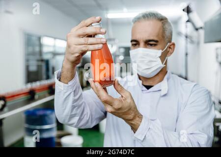 Quality control and food safety inspector test and check product contaminate standard in the food and drink factory production line with hygiene care. Stock Photo