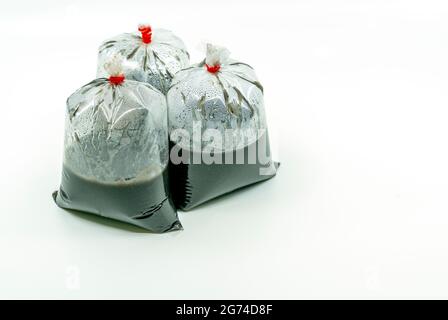 Black sesame soup in cleared plastic bag on white background for sell. Three bag of black sesame soups, tie with rubber band. Stock Photo