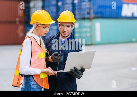 Logistic shipping worker team work working in shipping port cargo containers for export and import goods monitor with laptop computer. Stock Photo