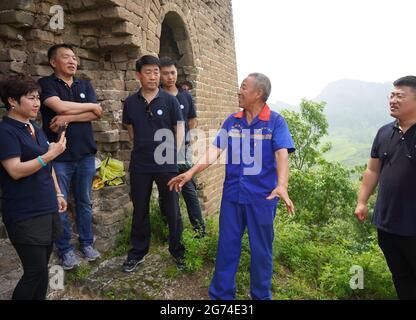 (210711) -- QINHUANGDAO, July 11, 2021 (Xinhua) -- Zhang Heshan (2nd R) introduces the Great Wall culture to tourists on the Chengziyu Great Wall in Qinhuangdao, north China's Hebei Province, July 7, 2021. Zhang Heshan, 66, is a villager of Chengziyu, where lies a section of China's Great Wall dating back to Ming Dynasty (1368-1644). Since 1978, Zhang has been a protector of the Great Wall. Over the years, he patrolled the wild Great Wall near his village and never been held back by various challenges, such as blizzards, rainstorms, wild bees and snakes. He has persuaded the herdsmen to le Stock Photo