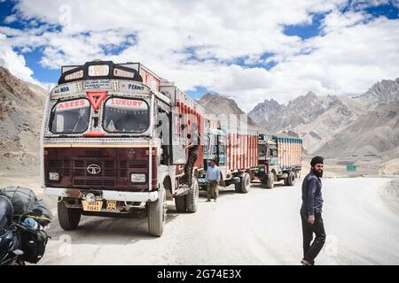 Tata trucks in himalyas. standing in line. Indian man working at the truck, man walking to the side. Indian mountain pass, Himalayas on a dusty road. Stock Photo