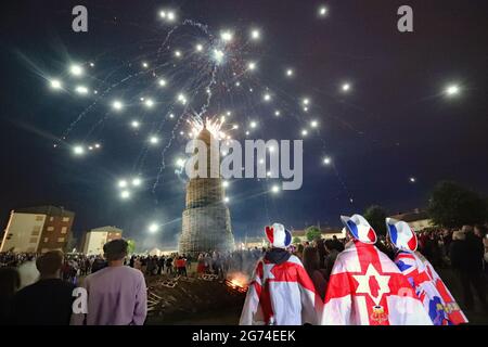 Crowds watch a fireworks display before the huge bonfire in the loyalist Corcrain area of Portadown, Co Armagh, is lit on the 'Eleventh night' to usher in the Twelfth commemorations. Picture date: Saturday July 10, 2021. Stock Photo