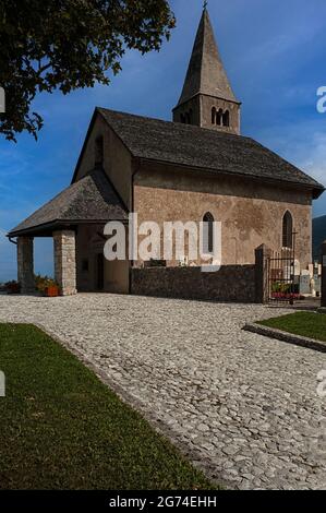 The medieval Chiesa di San Tommaso Apostolo (Church of St Thomas the Apostle) stands on an upland site above Cavedago, Trentino-Alto Adige, Italy, offering panoramic views of the rugged Brenta Dolomites. The church was badly damaged by fire in the early 1900s and lost its parochial function in 1974 but has since been fully restored. Stock Photo