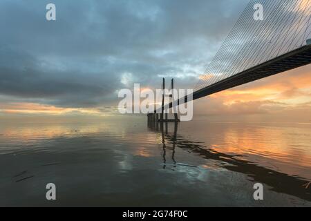 Background with colourful sunrise on the Lisbon bridge. The Vasco da Gama Bridge is a landmark, and one of the longest bridges in the world. Urban lan Stock Photo