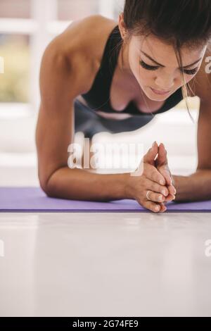 Young woman doing core exercise on fitness mat in the gym. Female holding plank pose in fitness studio. Stock Photo