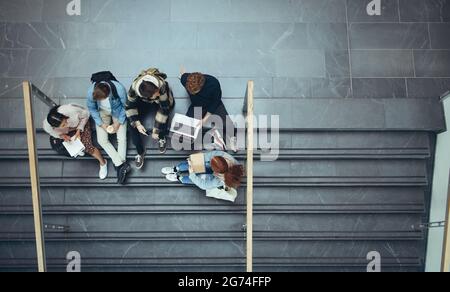 High angle view of students studying on stairs in college. Young people spending time together after class.