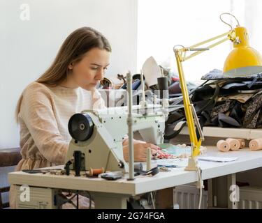 Focused female seamstress sewing clothes at her workplace Stock Photo