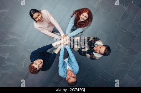 Top view of a young people standing and putting their hands together. Diverse students with hands stacked together. Stock Photo